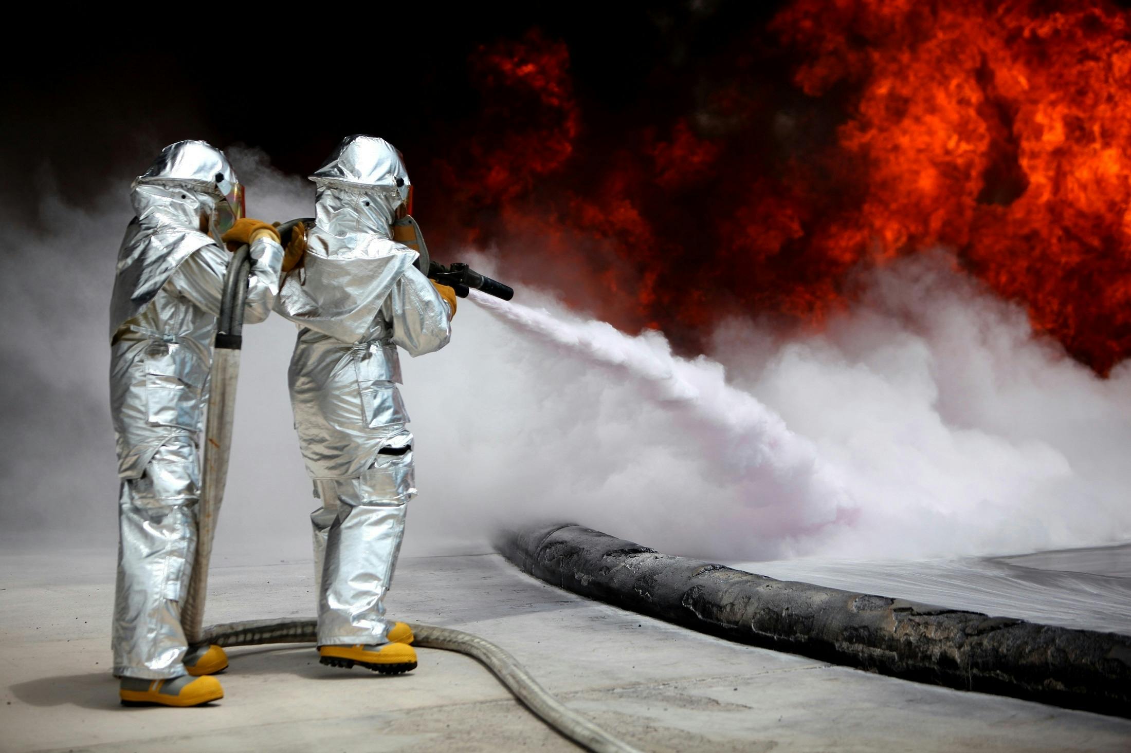 two firefighters trying to exting a fire with a hose, a photo, shutterstock, graffiti, wear spacesuits, oily substances, ap, silver