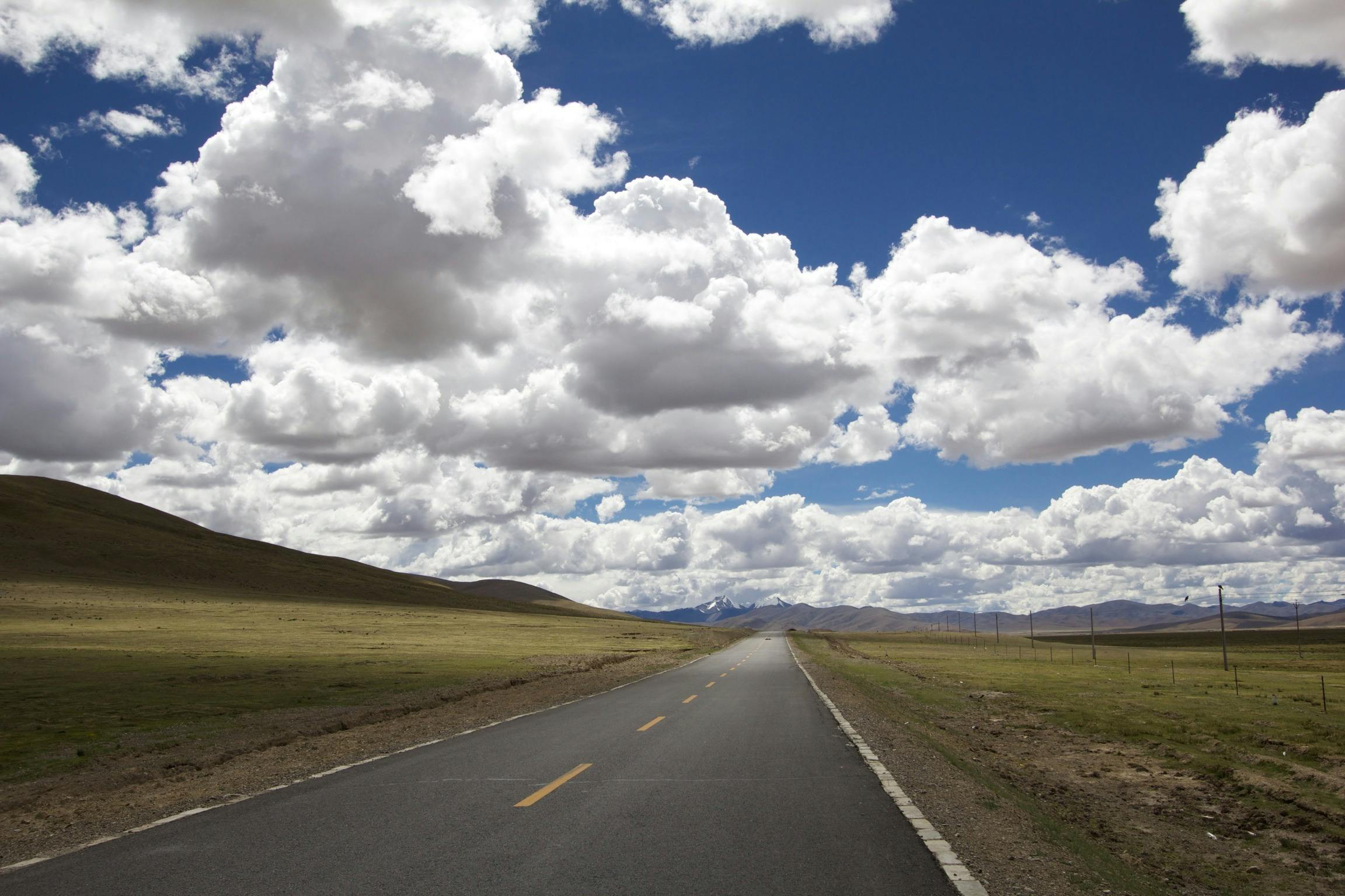 a road in the middle of a wide open field, unsplash, hurufiyya, tibet, prismatic cumulus clouds, high definition photo, album