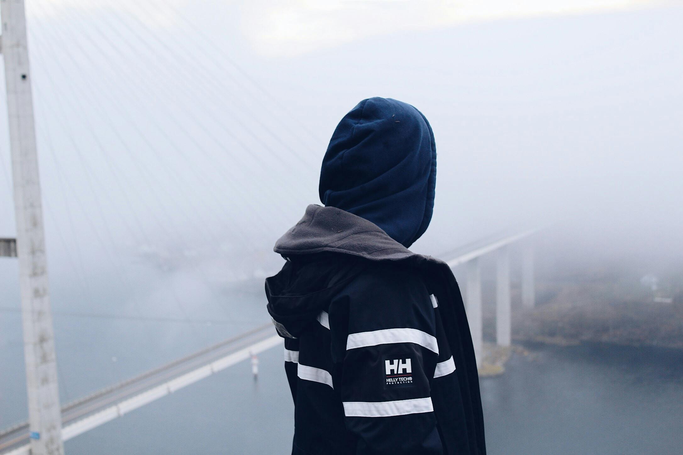 a person standing in front of a bridge on a foggy day, a picture, inspired by Hallsteinn Sigurðsson, happening, streetwear, profile image, high-resolution, high - resolution