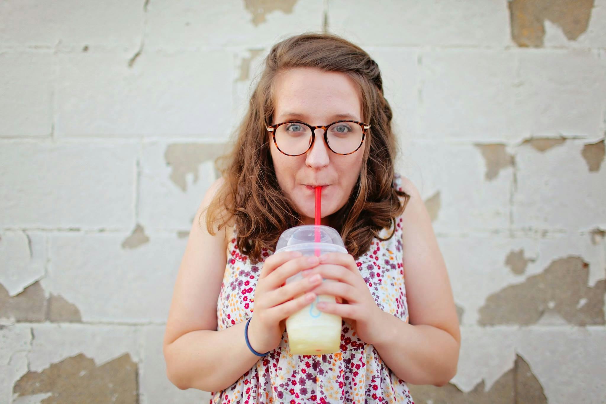 a woman holding a drink in front of her face, unsplash, ricky berwick, drink milkshakes together, alabama, profile image