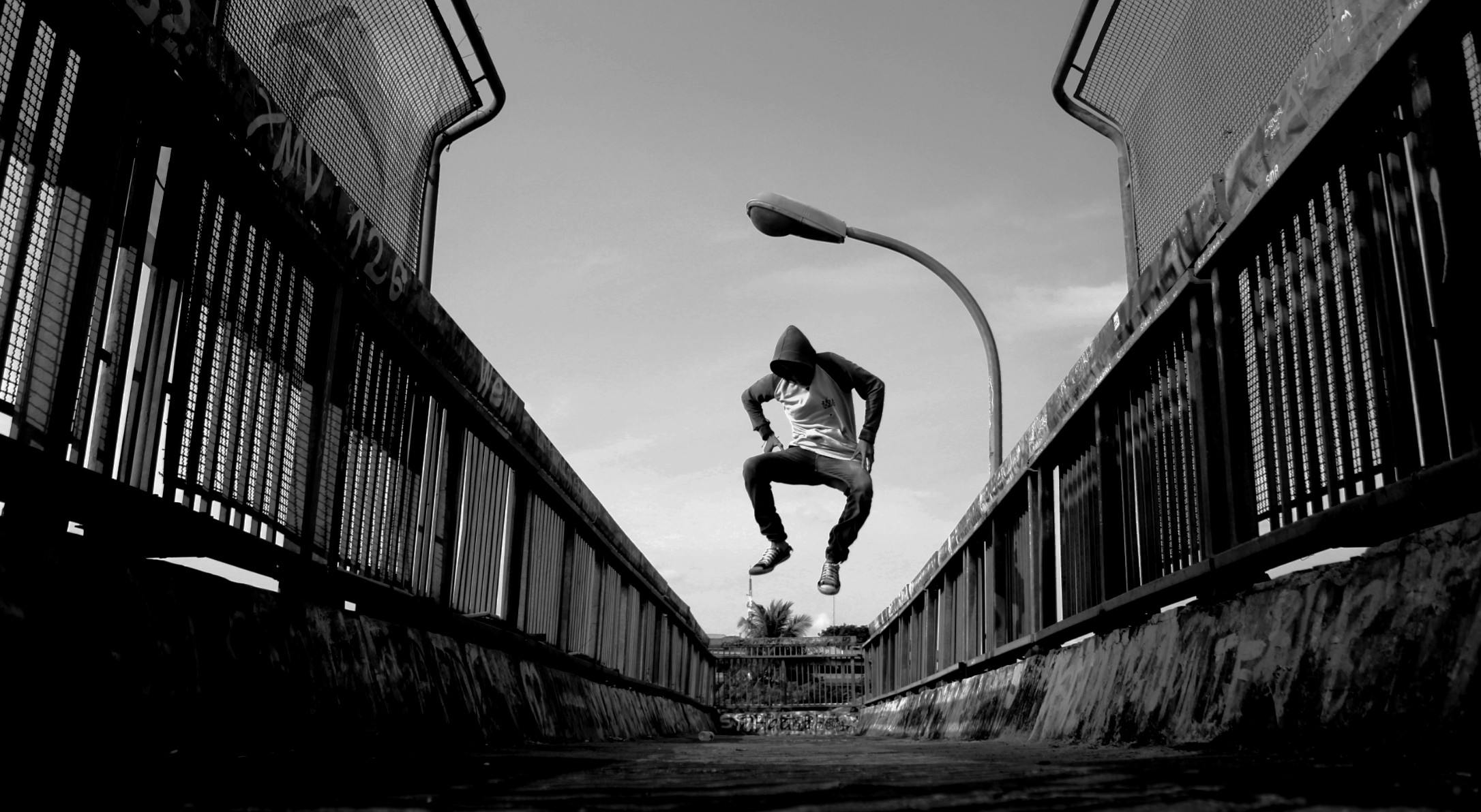 a man flying through the air while riding a skateboard, a black and white photo, by Joze Ciuha, unsplash, conceptual art, bridge, parkour, jumping at the viewer, hiphop