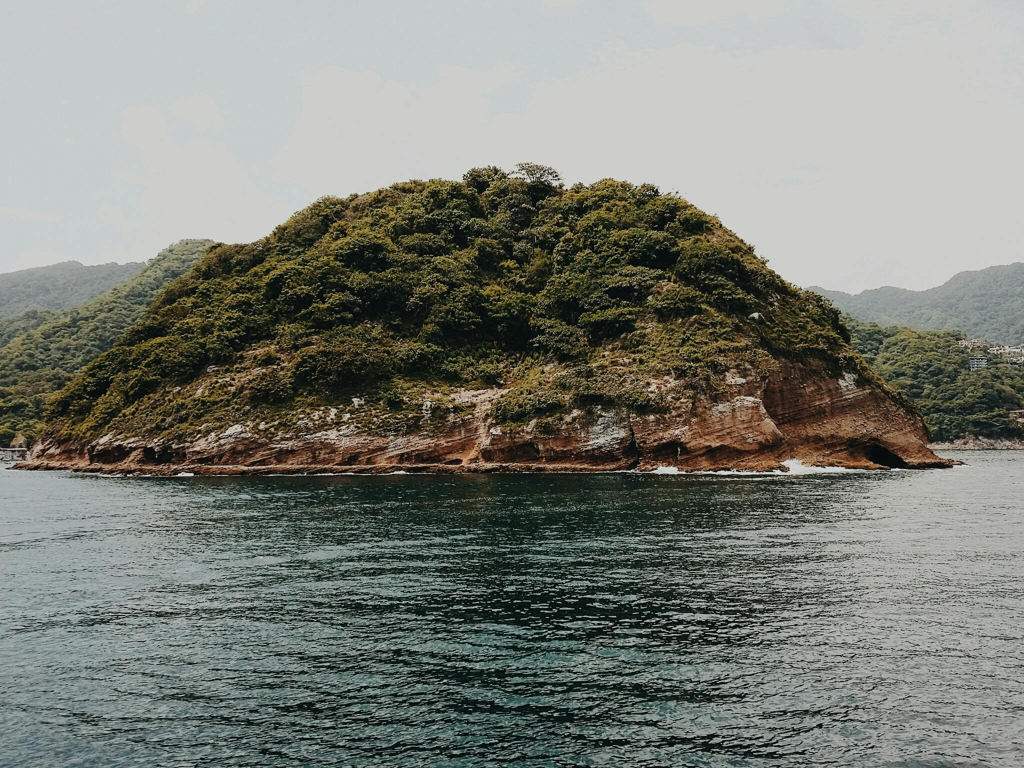 a small island in the middle of a body of water, an album cover, pexels contest winner, mingei, kamakura scenery, puerto rico, trending on vsco, rocky hills