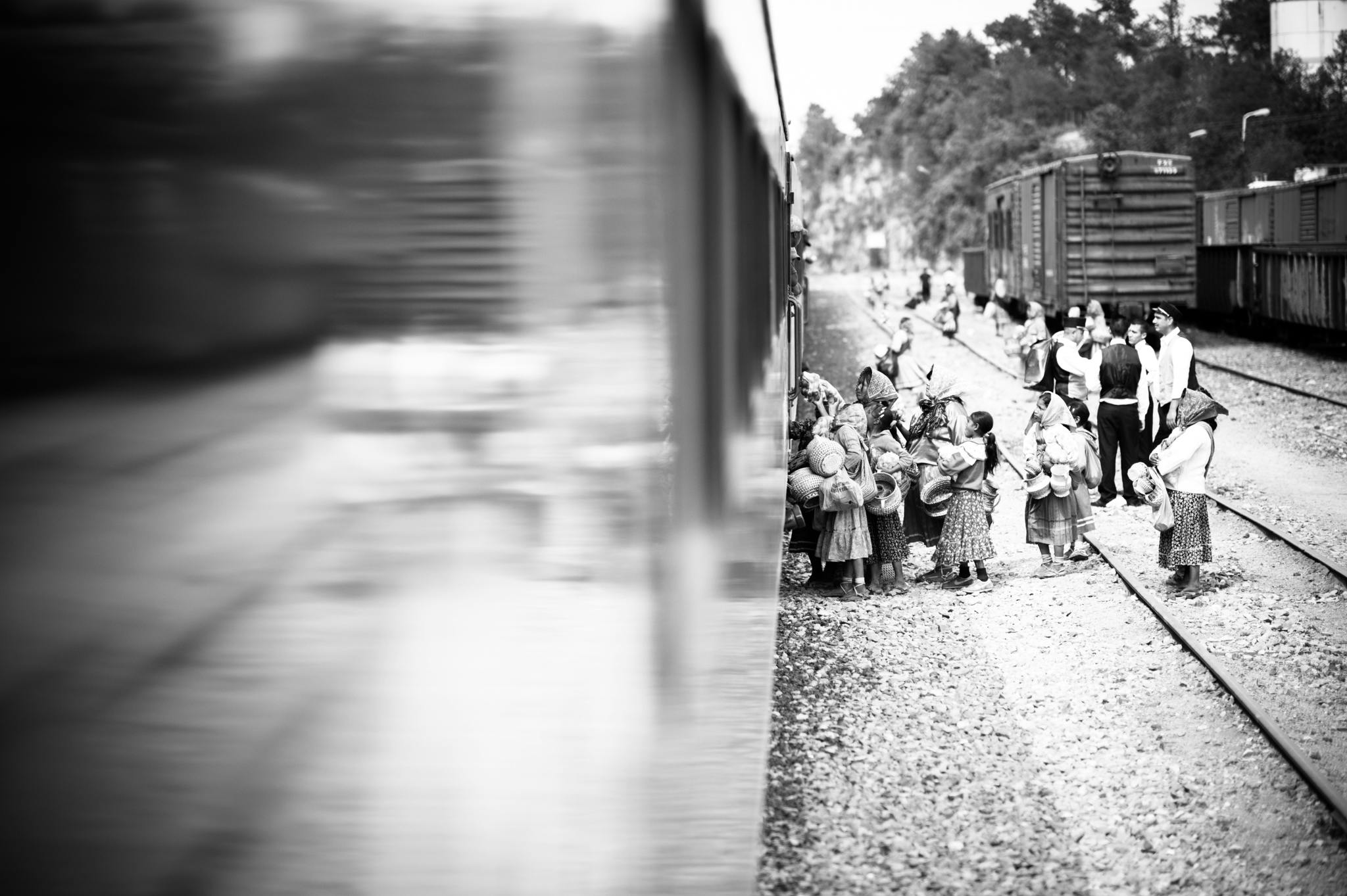 a group of people standing on a train track, a black and white photo, by Lucia Peka, unsplash, realism, the crowd flees the village, reflection, parents watching, by greg rutkowski