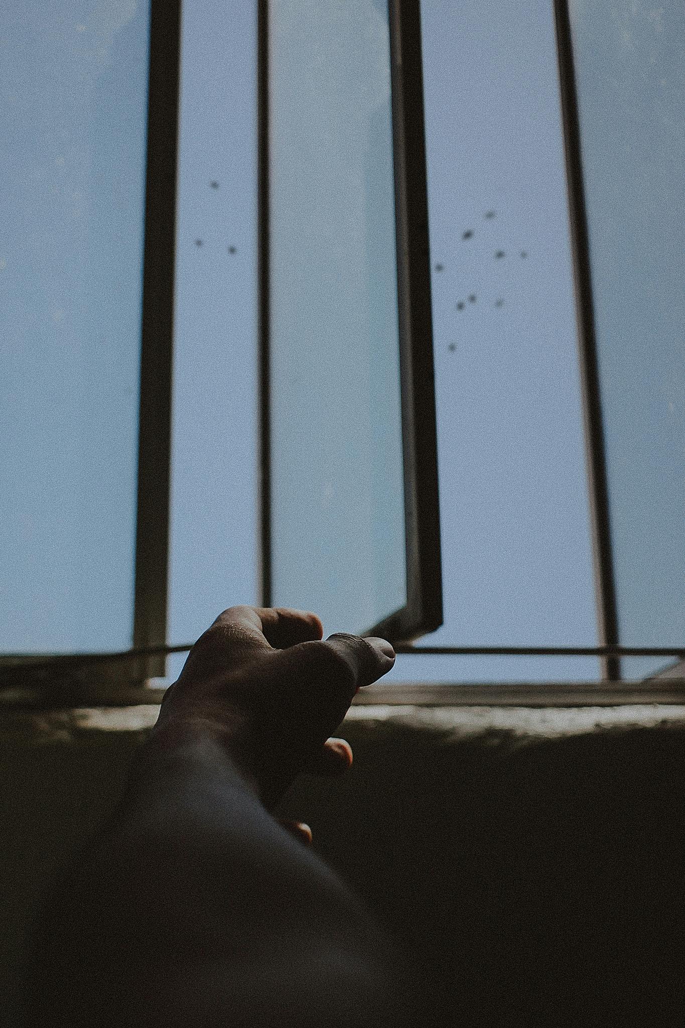 a person holding a cell phone in front of a window, an album cover, pexels contest winner, visual art, looking up onto the sky, scratches on photo, empty hands, bars on the windows