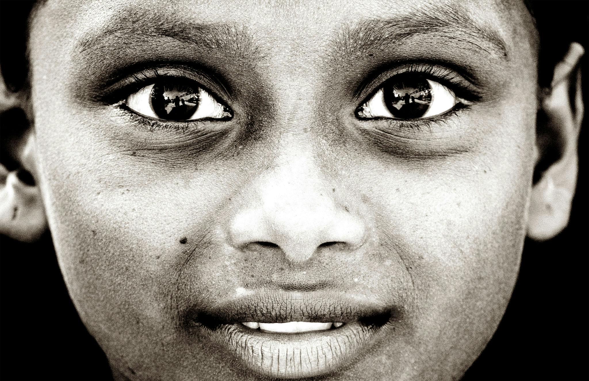 a black and white photo of a young boy, by Sudip Roy, pexels contest winner, hyperrealism, beautiful symmetrical eyes, indian girl with brown skin, face!!!! close - up, many eyes