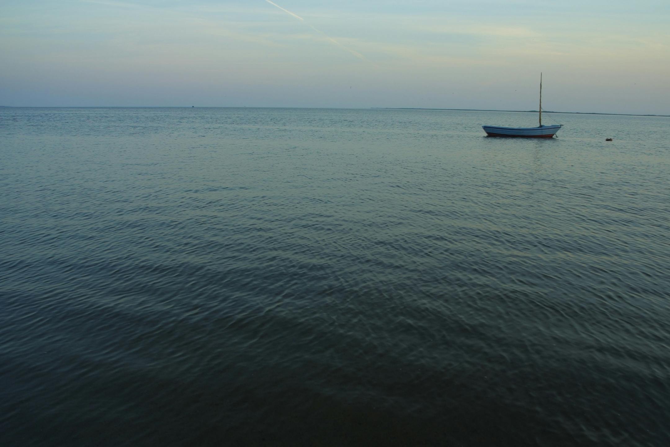 a boat floating on top of a large body of water, unsplash, fades to the horizon, 4 k film still, craigville, ignant