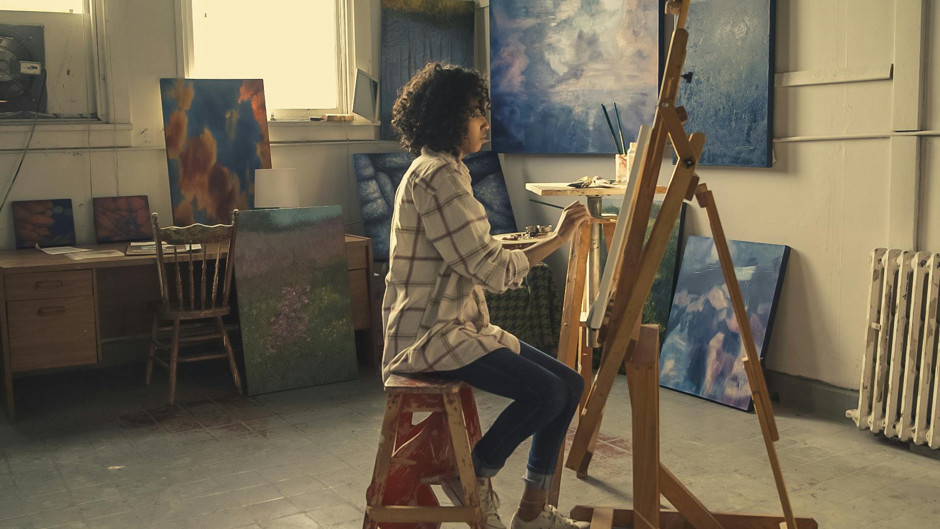 a woman with an easel and painting in a studio