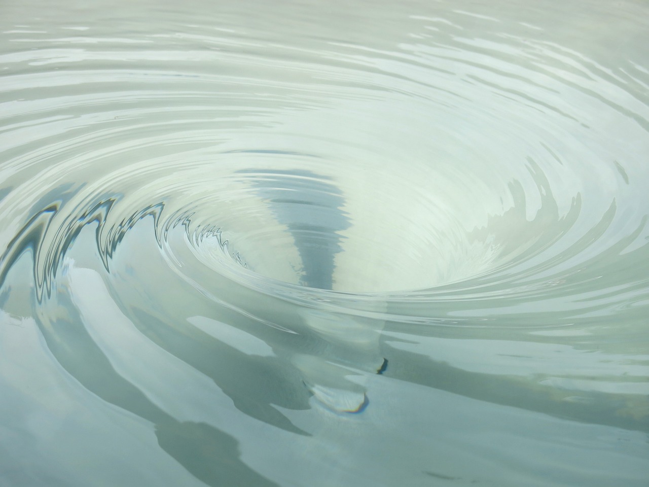 a close up of a wave in a body of water, a picture, inspired by Lucio Fontana, shutterstock, pulled into the spiral vortex, porcelain forcefield, muted water reflections, benjamin vnuk