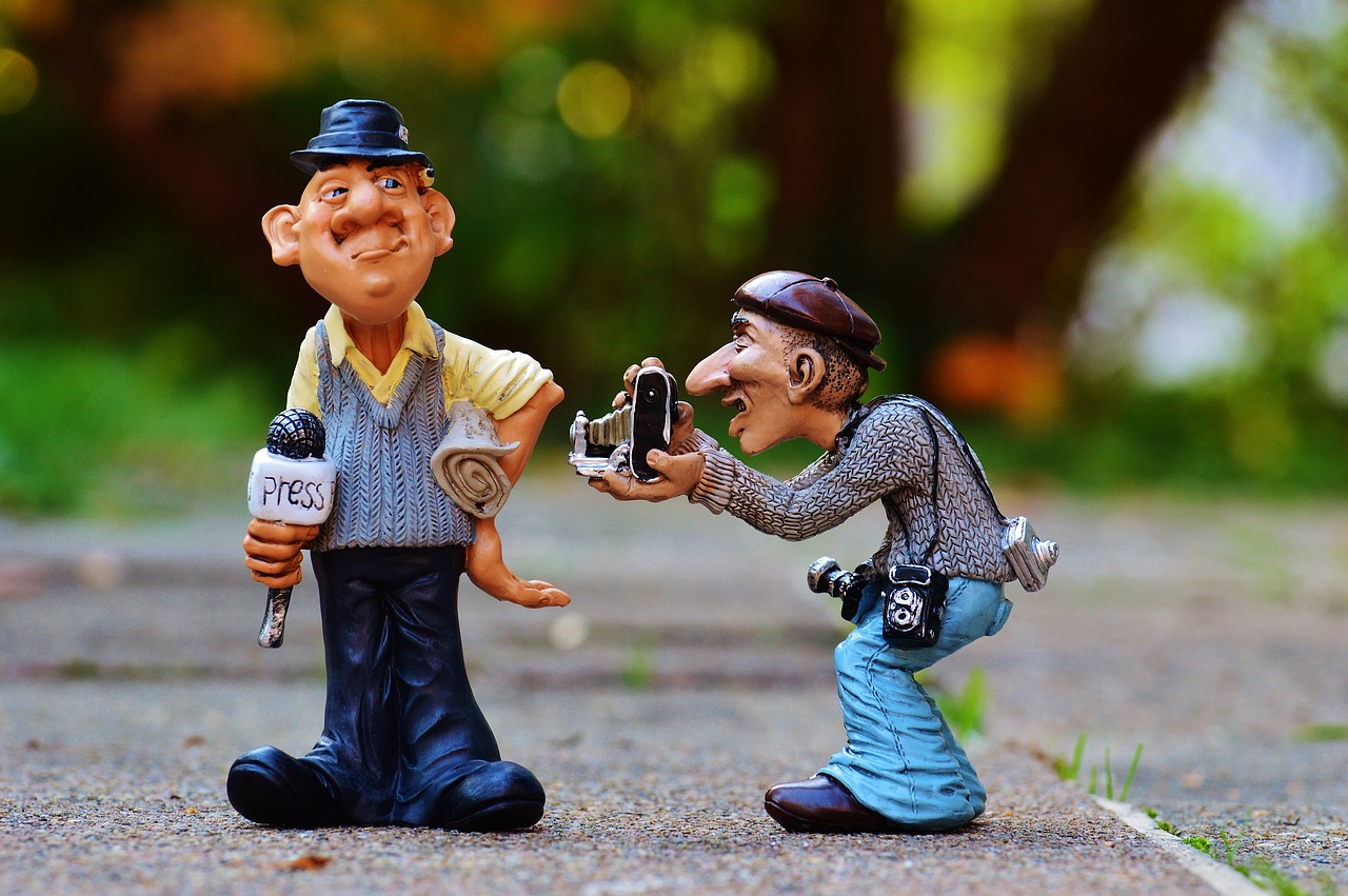 a figurine of a man taking a picture of another man, by Tom Carapic, pixabay contest winner, visual art, caricaturist, giving an interview, smiling at the camera, sculptures