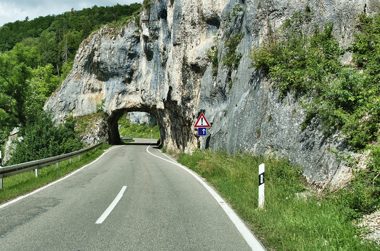 a couple of people standing on the side of a road, a photo, by Alfons von Czibulka, shutterstock, cave entrance, unobstructed road, maintenance photo, france