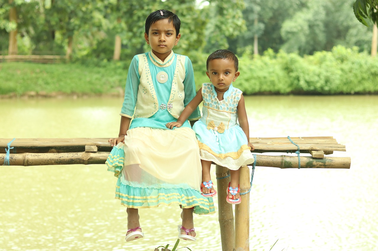 a couple of young girls sitting on top of a wooden bridge, by Odhise Paskali, flickr, hurufiyya, wearing bihu dress mekhela sador, cyan and green, real picture taken in zoo, sitting at a pond