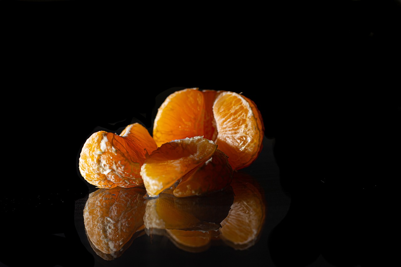 a close up of a peeled orange on a reflective surface, by Etienne Delessert, miniature product photo, dark vignette, crisp, snacks