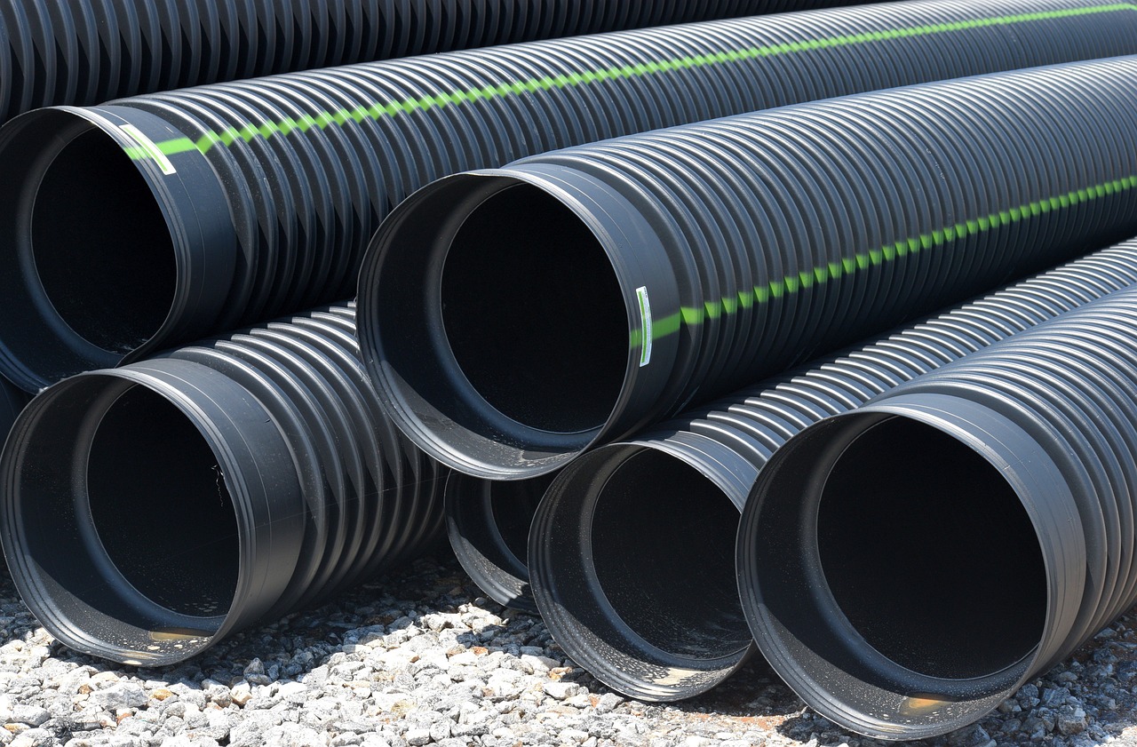 a pile of black plastic pipes sitting on top of gravel, half image, product introduction photo, a pair of ribbed, trenches
