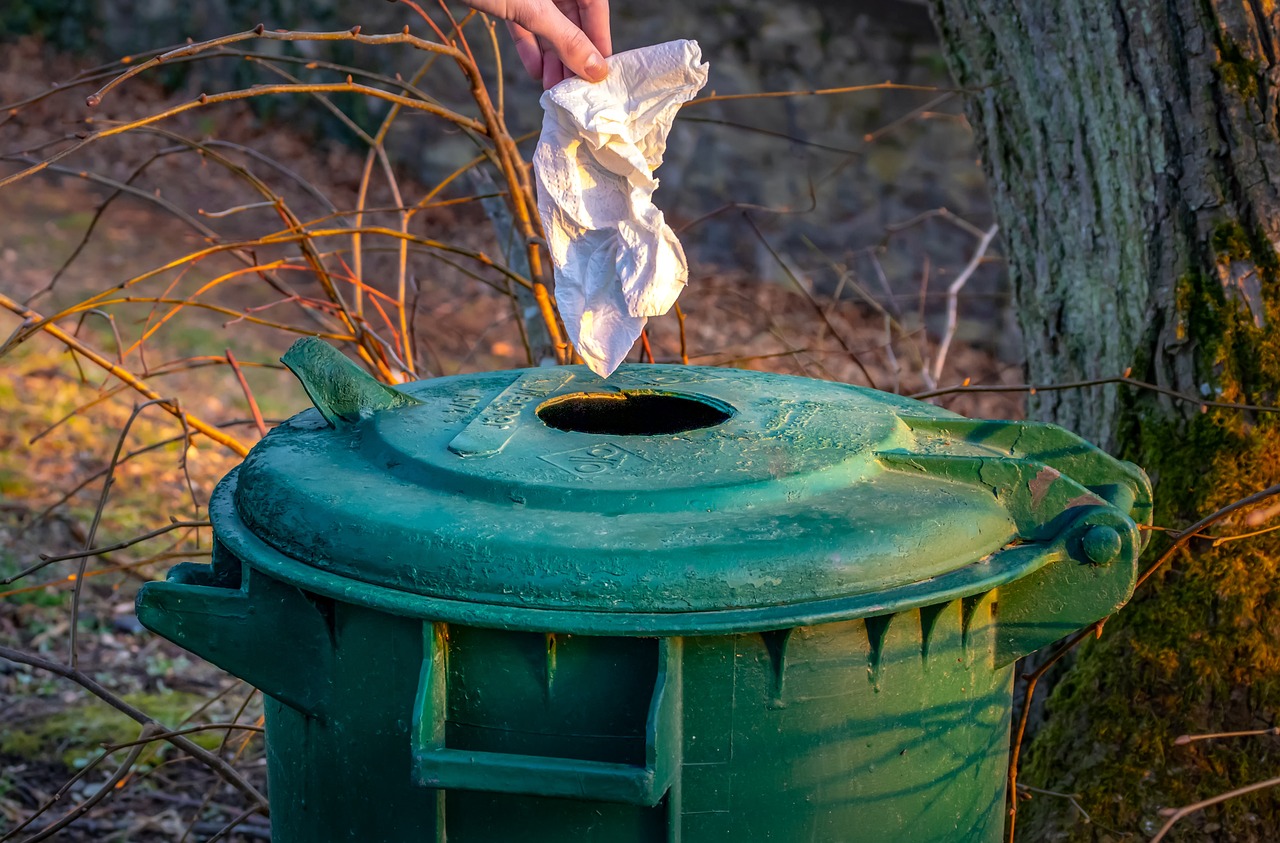 a person picking up a piece of paper from a trash can, a photo, by Jan Rustem, plasticien, gardening, taken at golden hour, green hood, rhode island