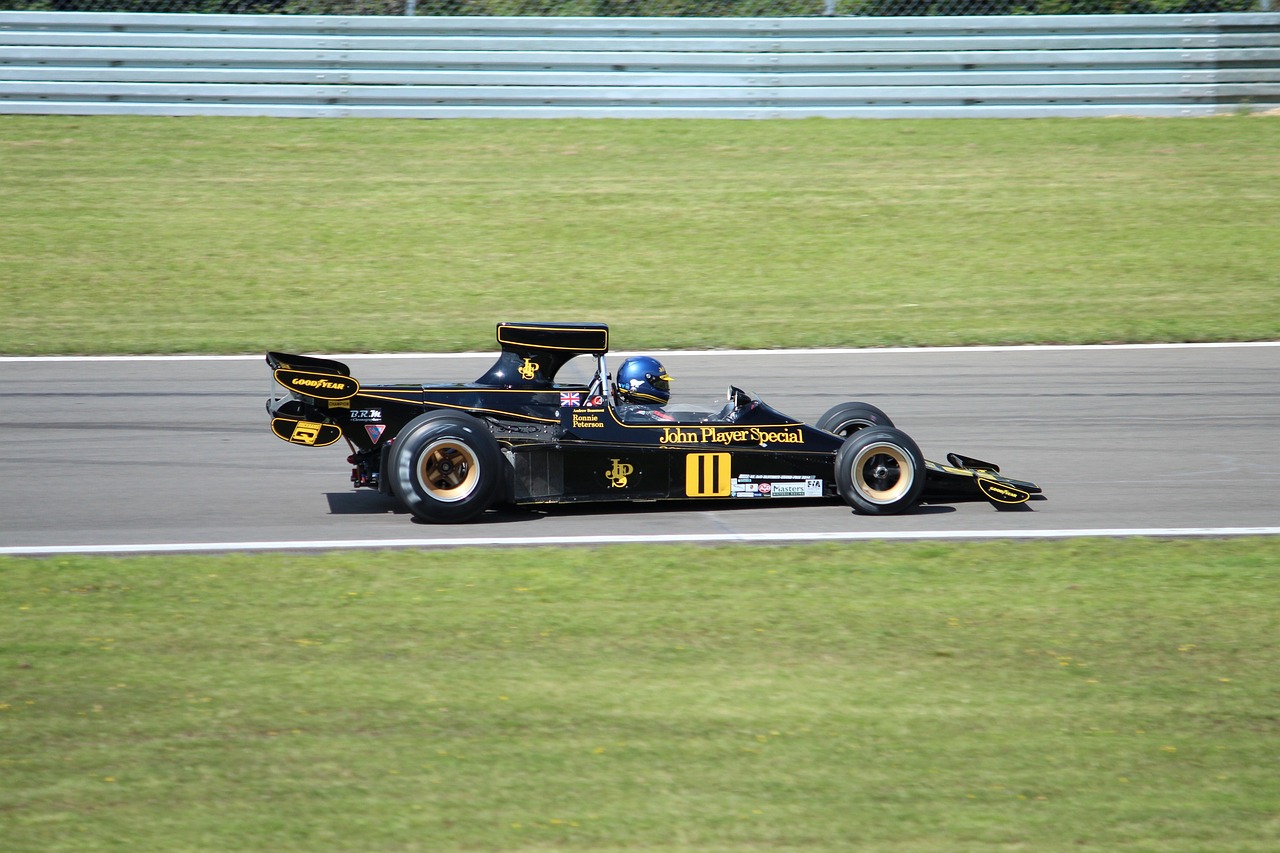 a man driving a race car on a track, a photo, flickr, gold and black color scheme, wikimedia commons, tjalf sparnaay 8 k, 7 0 s photo