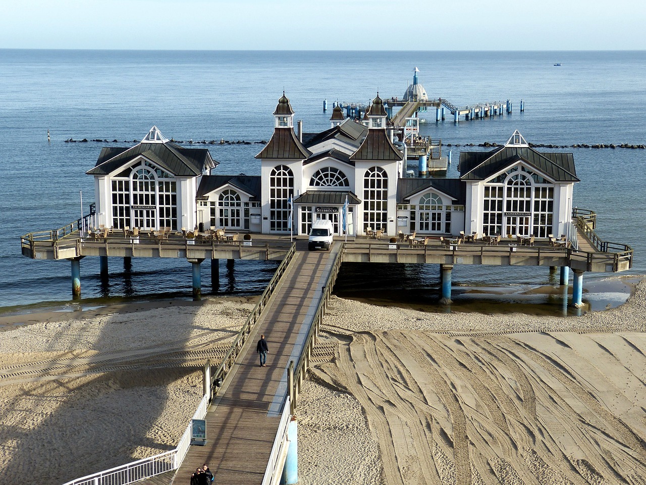 a pier sitting on top of a sandy beach next to the ocean, art nouveau, prussia, viewed from earth, casino, in 2 0 1 2