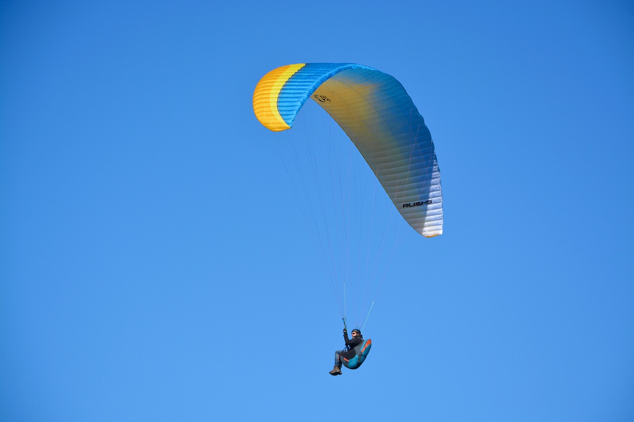 a person that is in the air with a parachute, a picture, by Julian Allen, shutterstock, blue and yellow color scheme, backlit!!, maui, fine wind