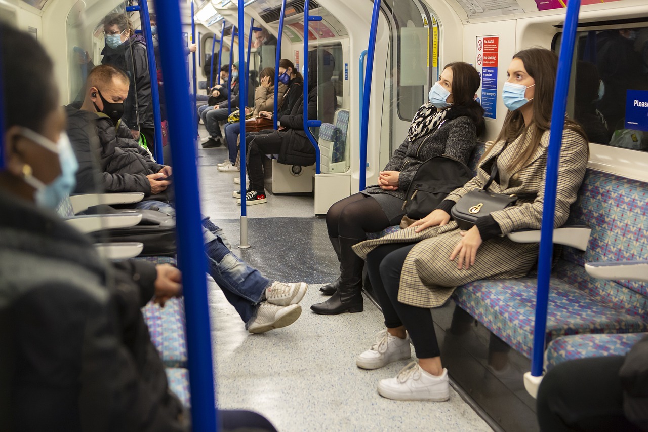 a group of people sitting next to each other on a train, a picture, by Robert Brackman, shutterstock, down in the sewers of london, people are wearing masks, stock photo, people on the ground