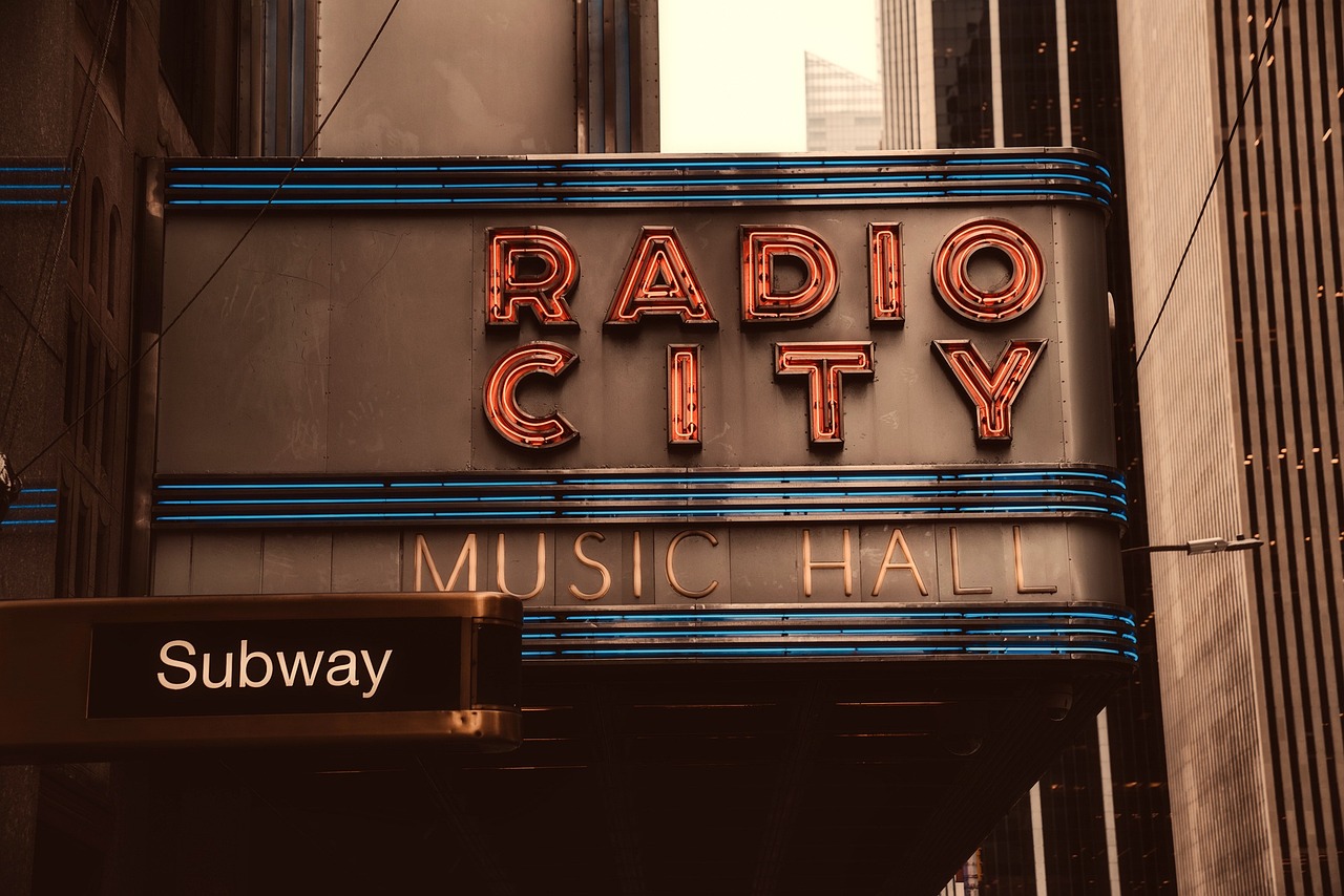 a radio city music hall sign on the side of a building, a colorized photo, shutterstock, graffiti, sepia photography, rainny, in a post apocalyptic city, album photo