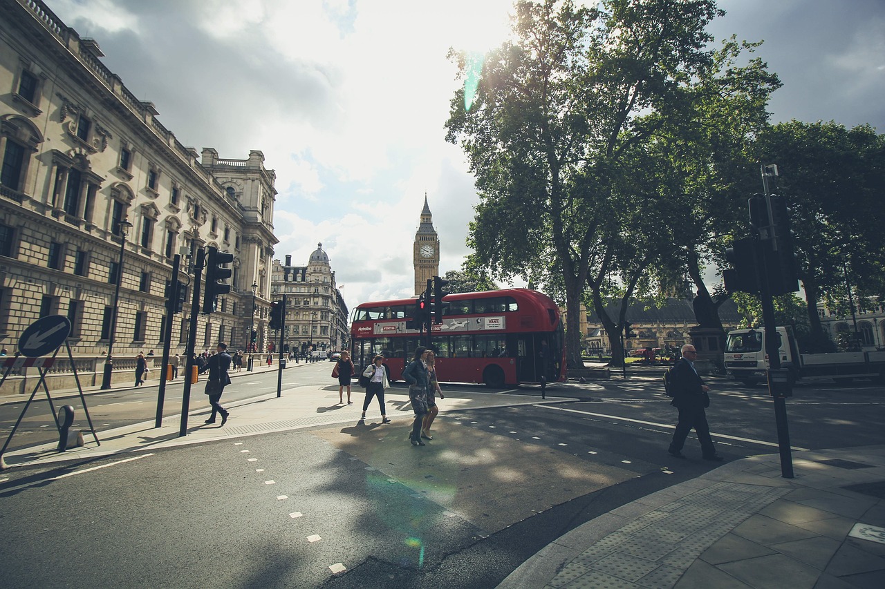 a red double decker bus driving down a street, a picture, by Nick Fudge, shutterstock, visual art, people walking around, landscape photo, dapped light, circle