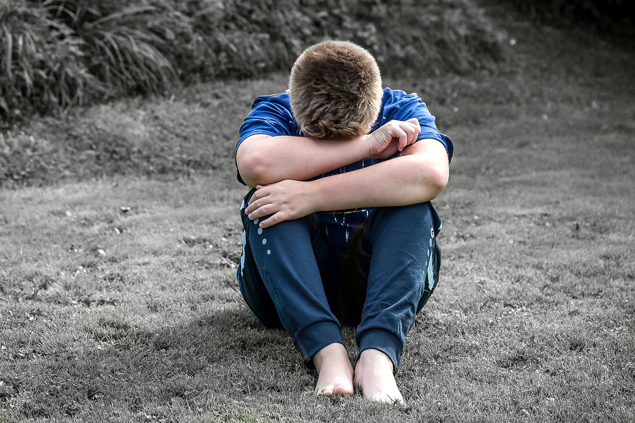 a boy sitting on the ground with his head in his hands, a photo, pixabay, heartbroken, john egbert, with his back turned, crying big blue tears