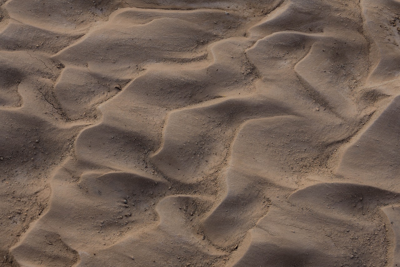 a red fire hydrant sitting on top of a sandy beach, a picture, by Etienne Delessert, land art, 4 k seamless mud texture, footprints in the sand, photograph from above, flowing curves