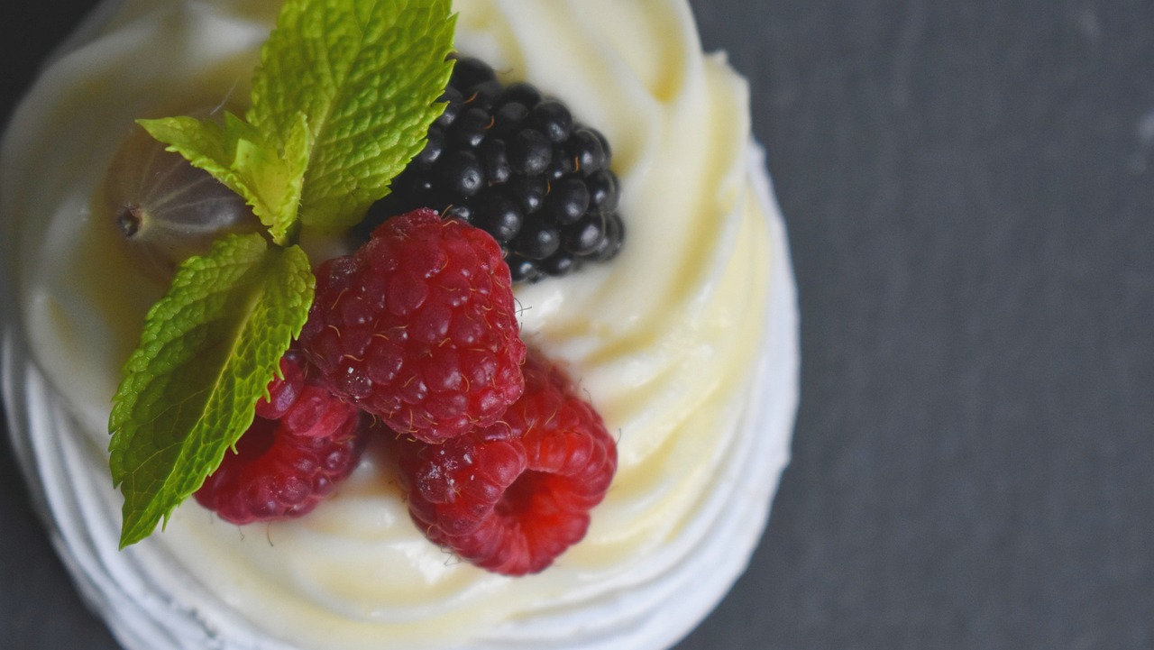 a cupcake topped with whipped cream and raspberries, by Adam Manyoki, unsplash, renaissance, 4k detail, fresh fruit, spiraling, photorealistic ”