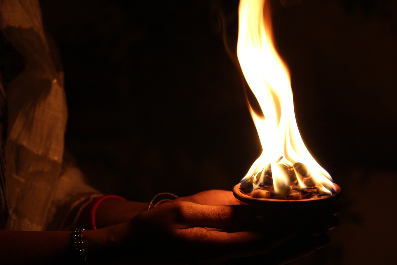 a person holding a lit candle in their hand, hurufiyya, wearing tumultus flames, hindu aesthetic, the sacred cup of understading, wikimedia commons