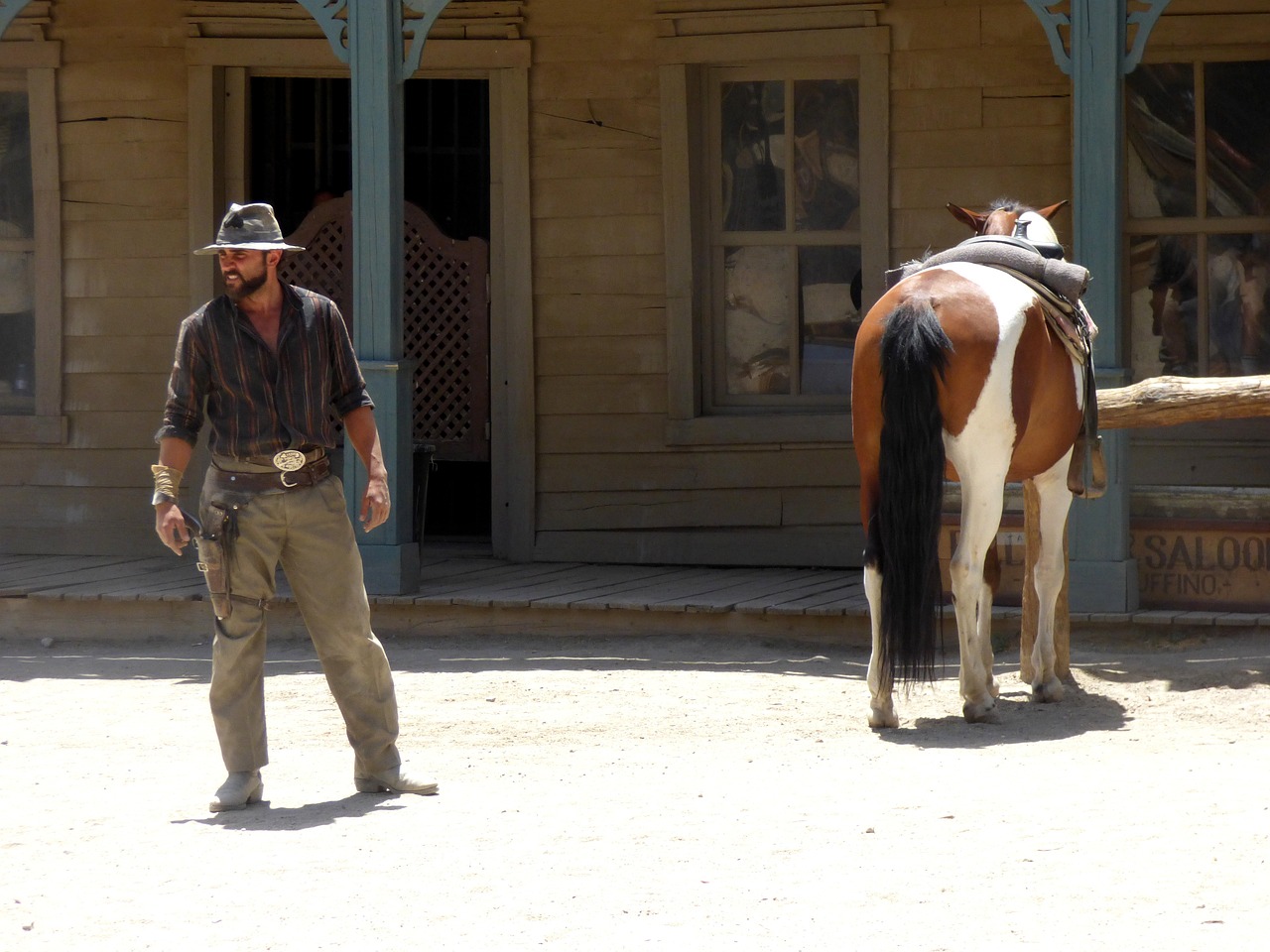 a man standing next to a horse in front of a building, by Linda Sutton, flickr, figuration libre, dressed as a western sheriff, scene from live action movie, scorching heat, california