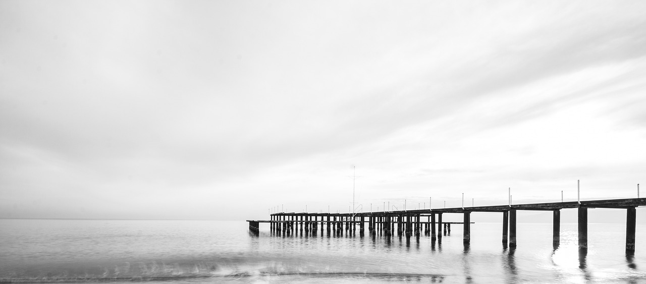 a black and white photo of a pier, by Raymond Normand, unsplash, minimalism, melbourne, high - key photography, seaside, silence