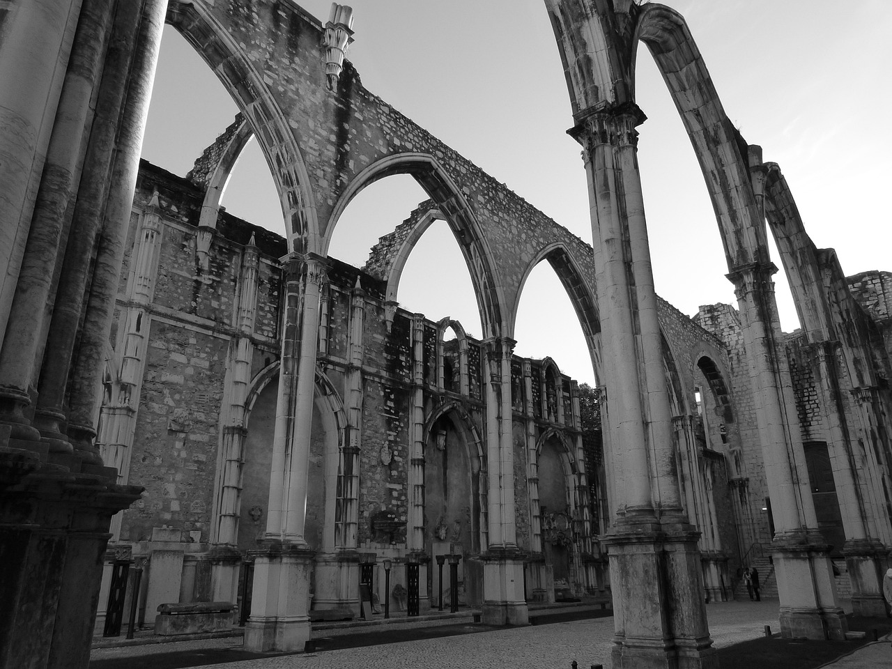 a black and white photo of an old building, by Nadir Afonso, pexels contest winner, romanesque, huge support buttresses, mossy ruins, calatrava, rust