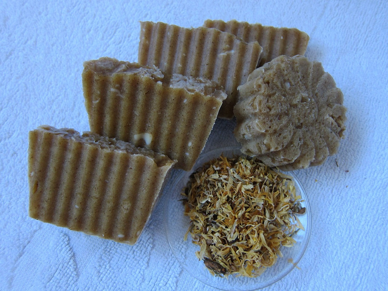 a group of soap bars sitting on top of a white towel, inspired by Géza Dósa, flickr, gold flaked flowers, roots and hay coat, highly detailed”, bee