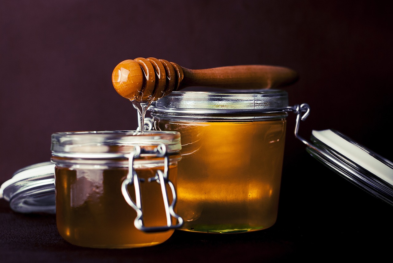 a couple of jars of honey sitting on top of a table, by Thomas Häfner, culinary art photography, spoon, screencap, bongos