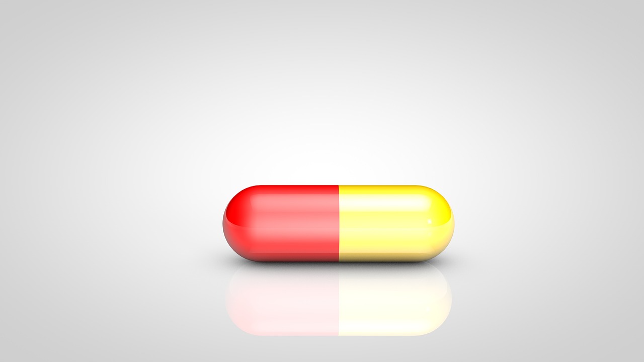 a red and yellow pill sitting on top of a white surface, a picture, high res photo, on a gray background, no gradients, mouse photo