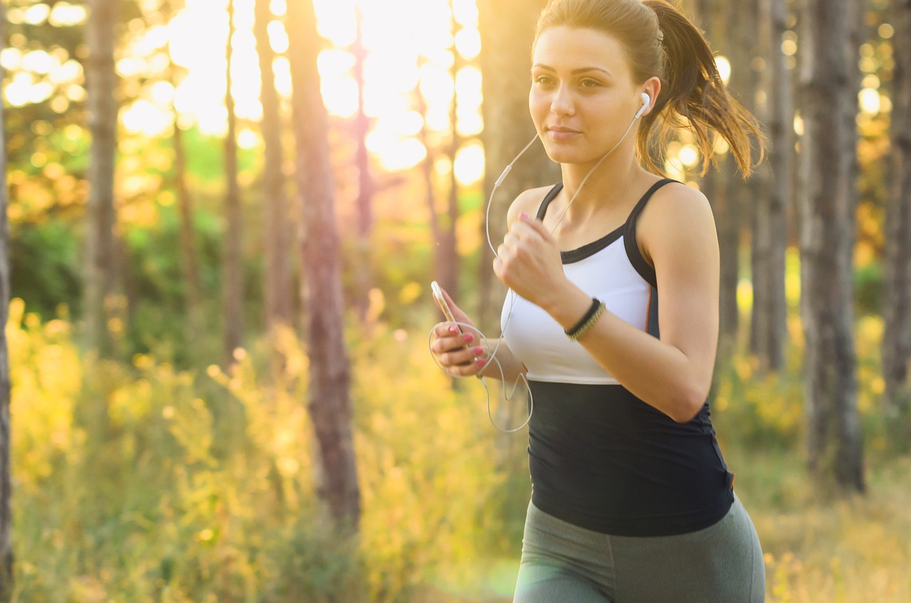 a woman is jogging and listening to music, a picture, by Mirko Rački, shutterstock, golden sunlight, cute girl, against the backdrop of trees, lower quality