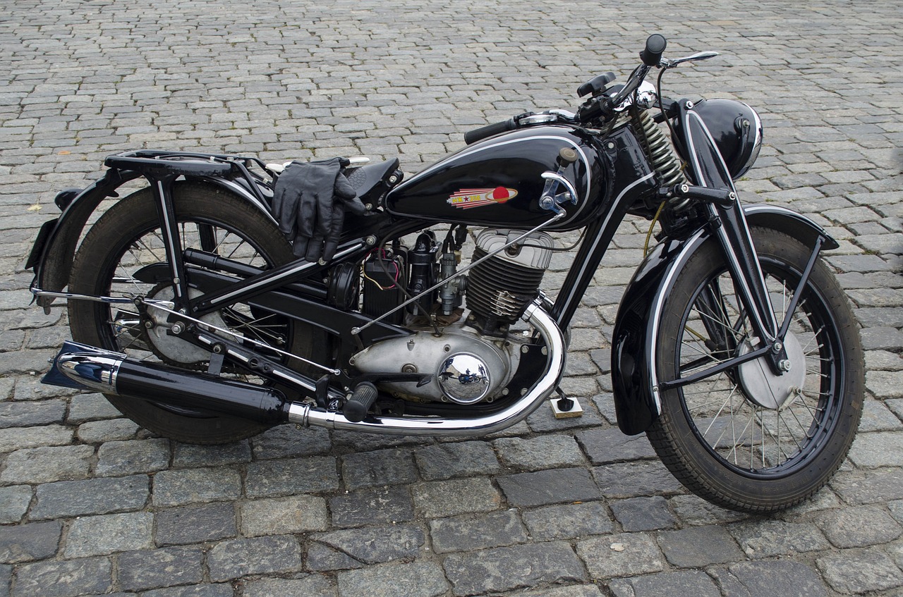 a black motorcycle parked on a cobblestone street, inspired by Otto Meyer-Amden, flickr, bauhaus, vintage - w 1 0 2 4, in a sunbeam, on display in a museum, s line