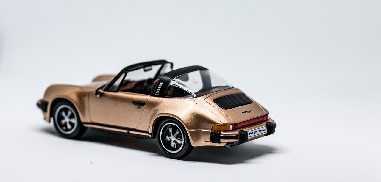 a close up of a toy car on a white surface, by Sebastian Spreng, unsplash, photorealism, brown and gold, porche, back turned, hq 4k phone wallpaper