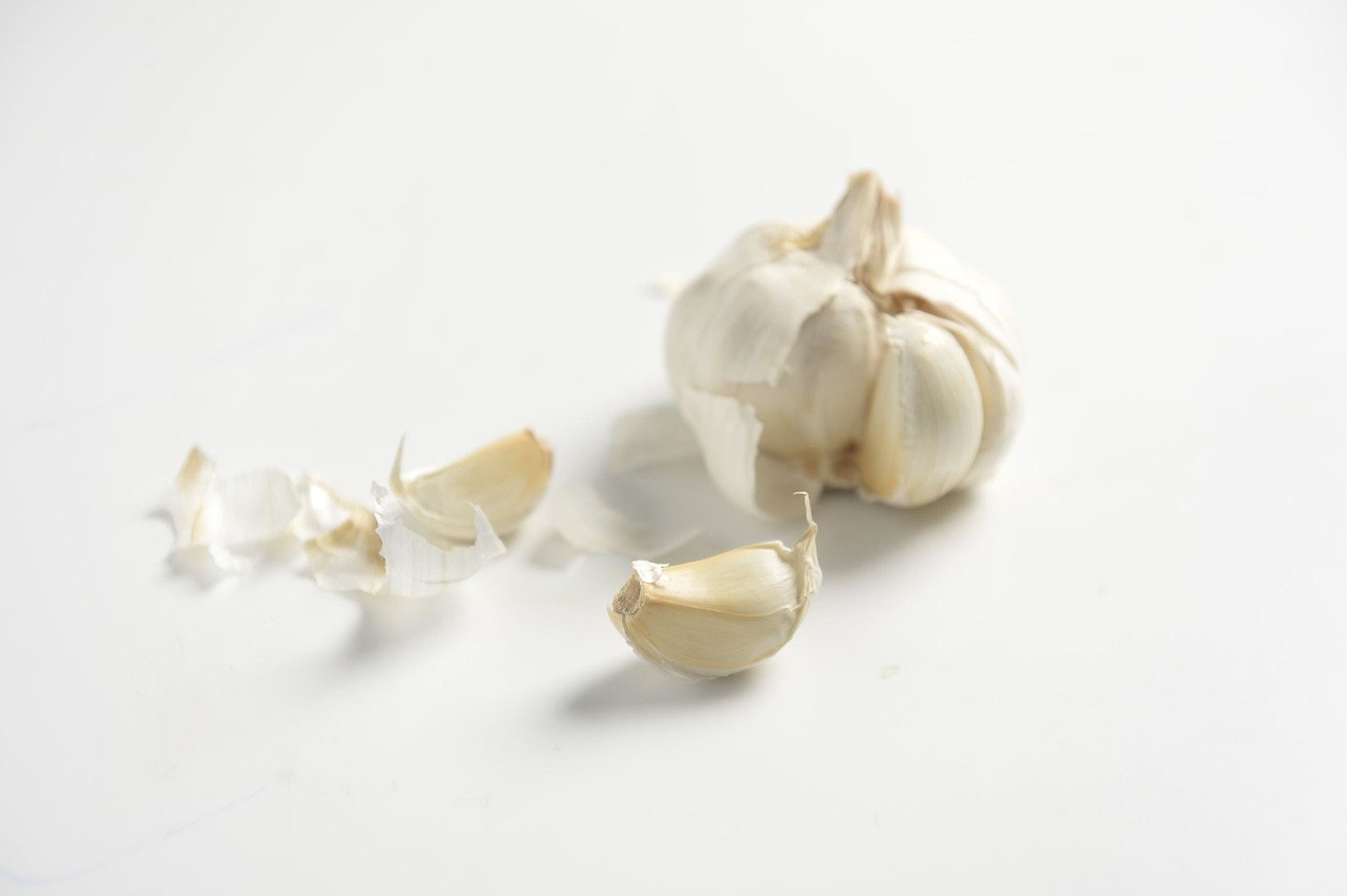 a clove of garlic next to a clove of garlic, a macro photograph, pexels, hurufiyya, on a white background, high detail product photo, injured, white hair floating in air