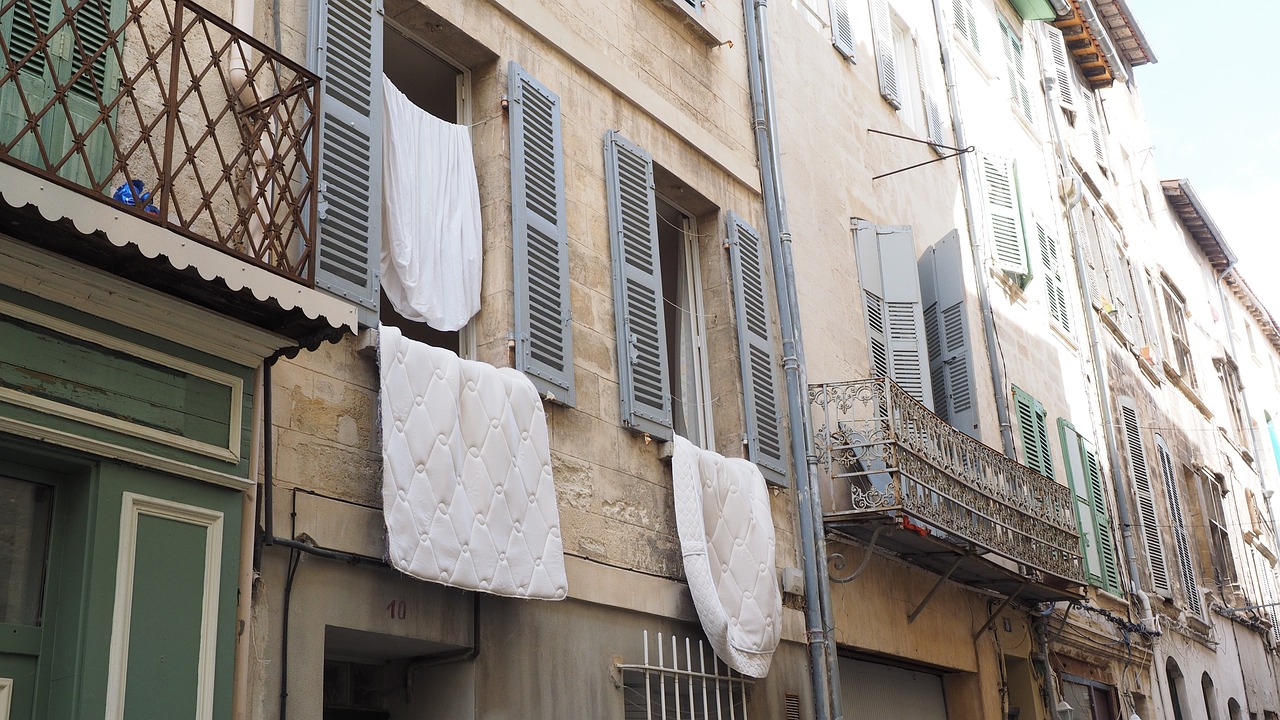 a building with clothes hanging out of the windows, inspired by Louise Bourgeois, flickr, white pillows, lourmarin, flowing silk sheets, bad quality