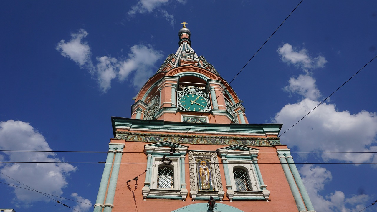 a clock that is on the side of a building, by Andrei Kolkoutine, art nouveau, in orthodox church, orange and teal color, lead - covered spire, russian and japanese mix