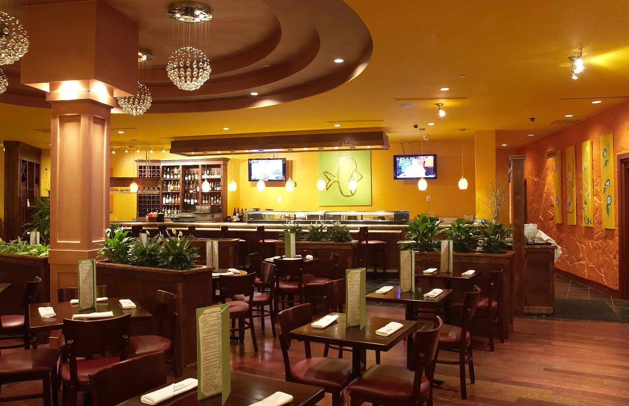 a restaurant filled with lots of tables and chairs, by Susan Heidi, yellow and olive color scheme, warm lighting interior, family friendly, large screen