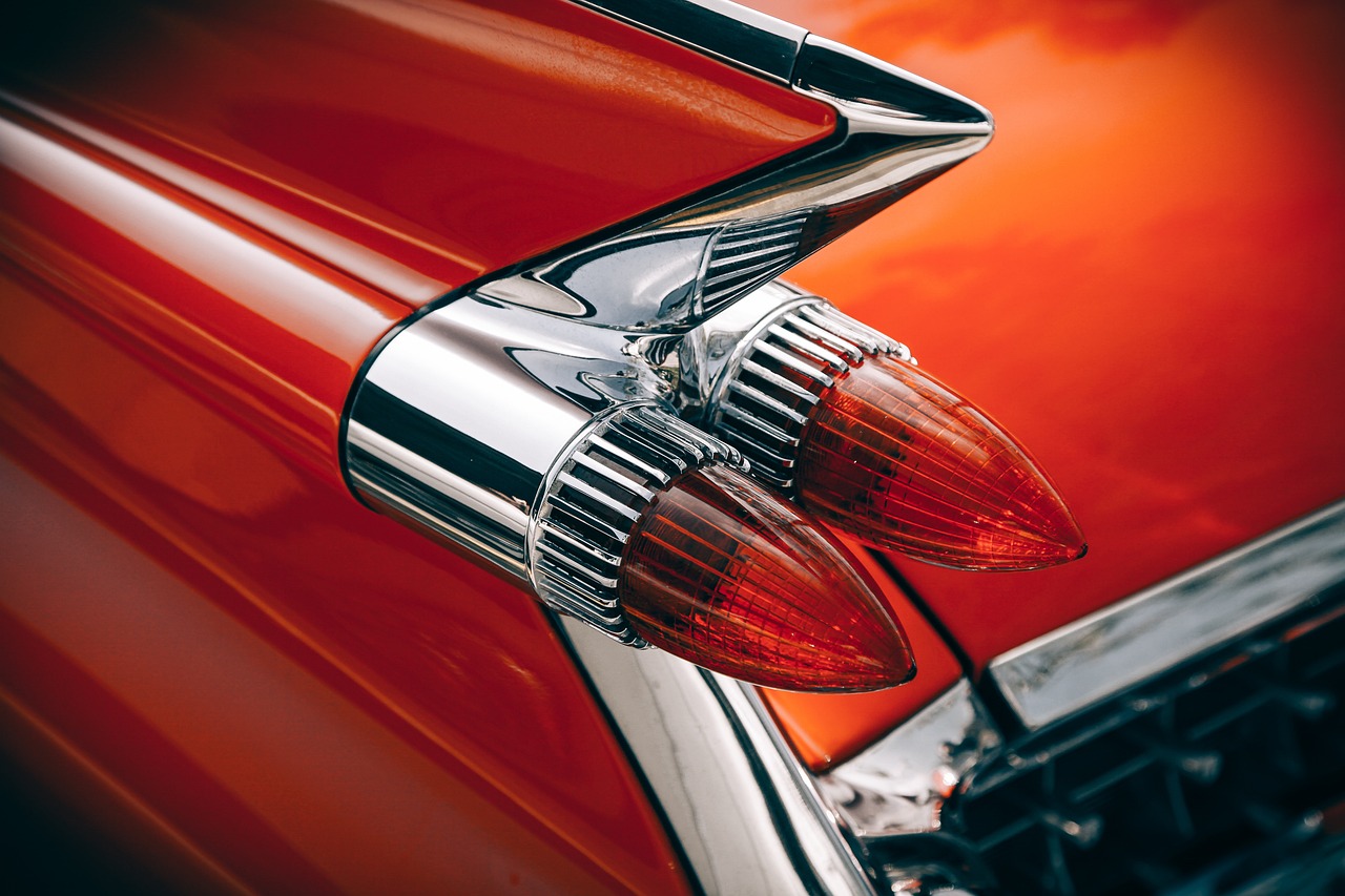 a close up of a red car's tail light, by Joe Bowler, pexels contest winner, photorealism, vintage colours 1 9 5 0 s, electric orange glowing lights, with big chrome tubes, cone shaped