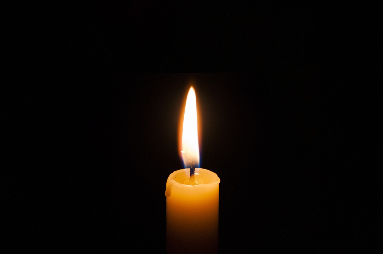 a single candle is lit in the dark, a picture, in the middle of the day, istockphoto, yellow lighting from right, on black background