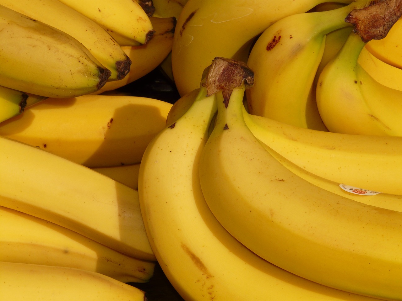 a bunch of bananas sitting on top of each other, a photo, detailed zoom photo, very known photo, 1128x191 resolution, outdoor photo