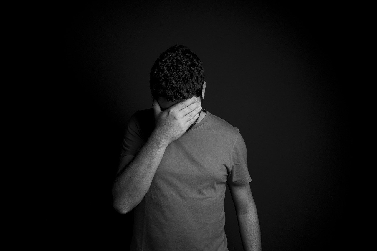 a black and white photo of a man covering his face, a black and white photo, minimalism, heartbroken, shot at dark with studio lights, a person standing in front of a, half body photo