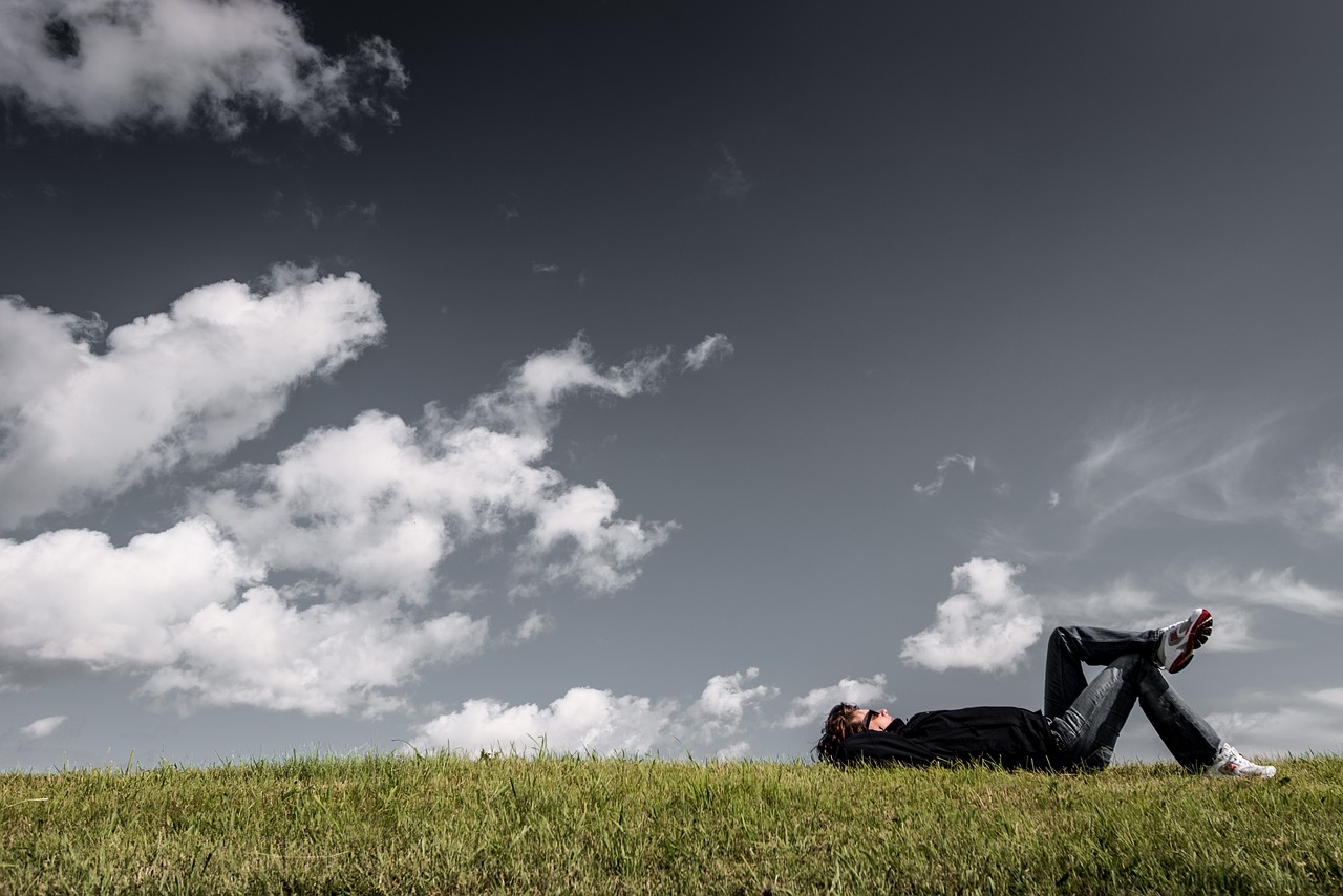 a man laying on top of a lush green field, a picture, by Matthias Weischer, precisionism, peaceful puffy clouds, relaxing after a hard day, benjamin vnuk, breathing