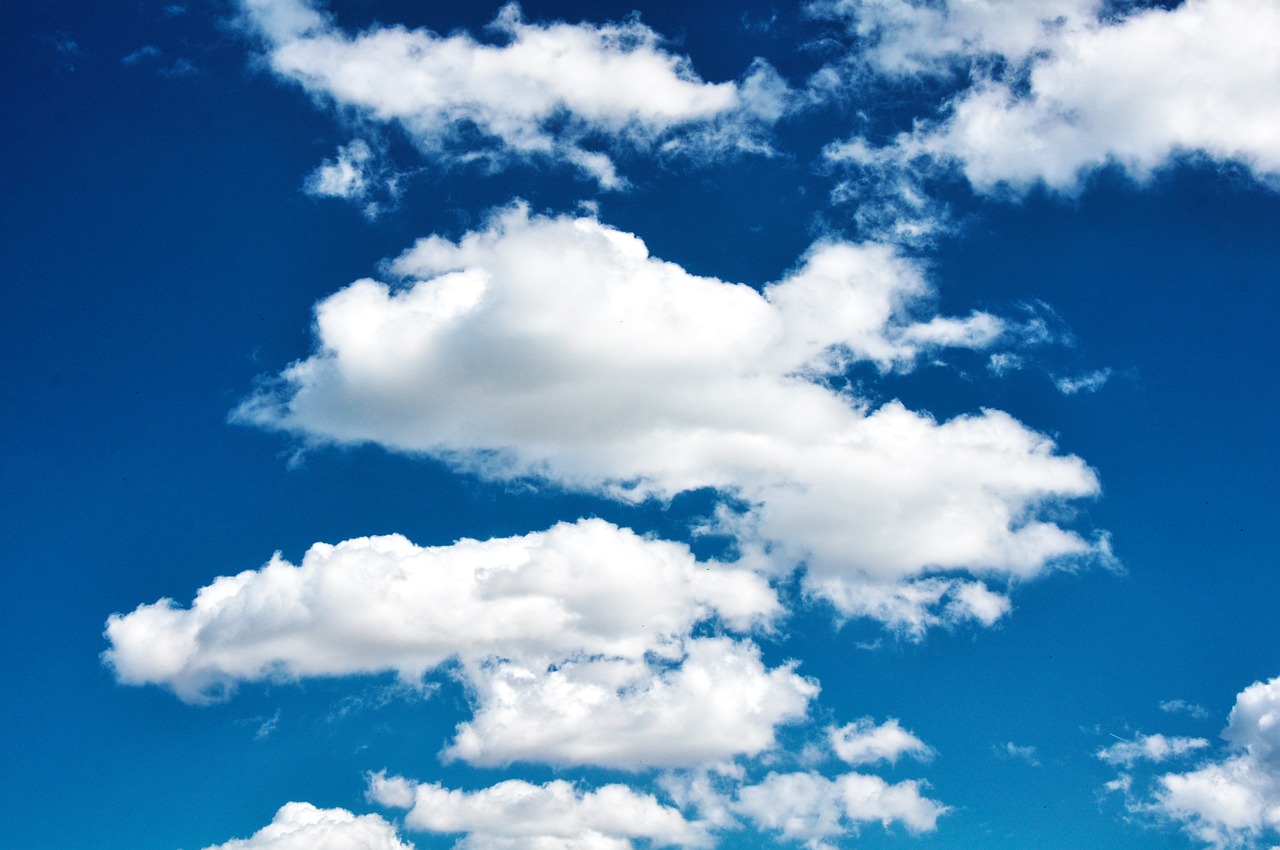 a group of people riding skis on top of a snow covered slope, a stock photo, shutterstock, minimalism, beautiful sky with cumulus couds, wallpaper - 1 0 2 4, “puffy cloudscape, blue sky with a few clouds