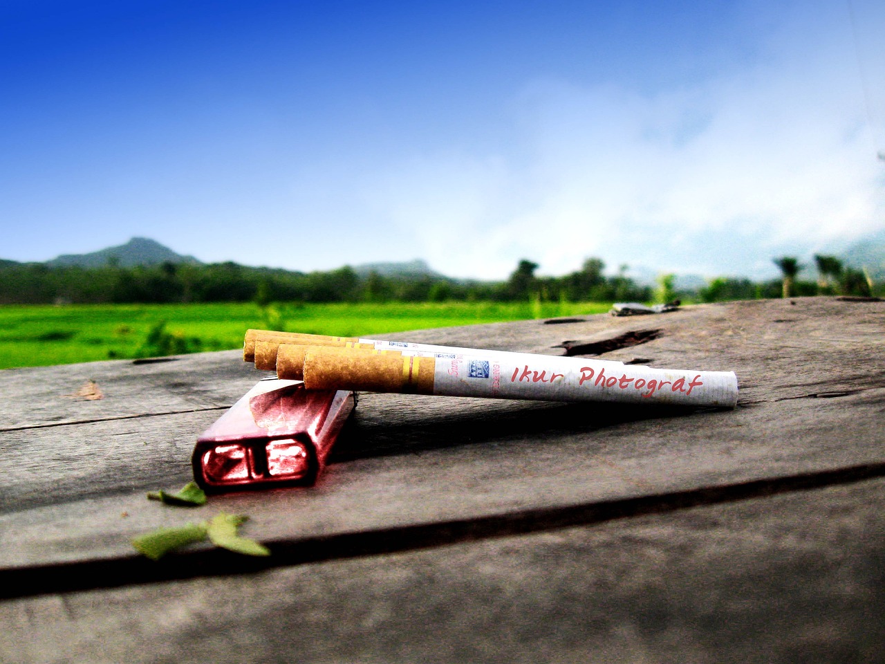 a cigarette sitting on top of a wooden table, a picture, by Daryush Shokof, sumatraism, in field high resolution, hyperrealistic flickr:5, roadside, pc wallpaper