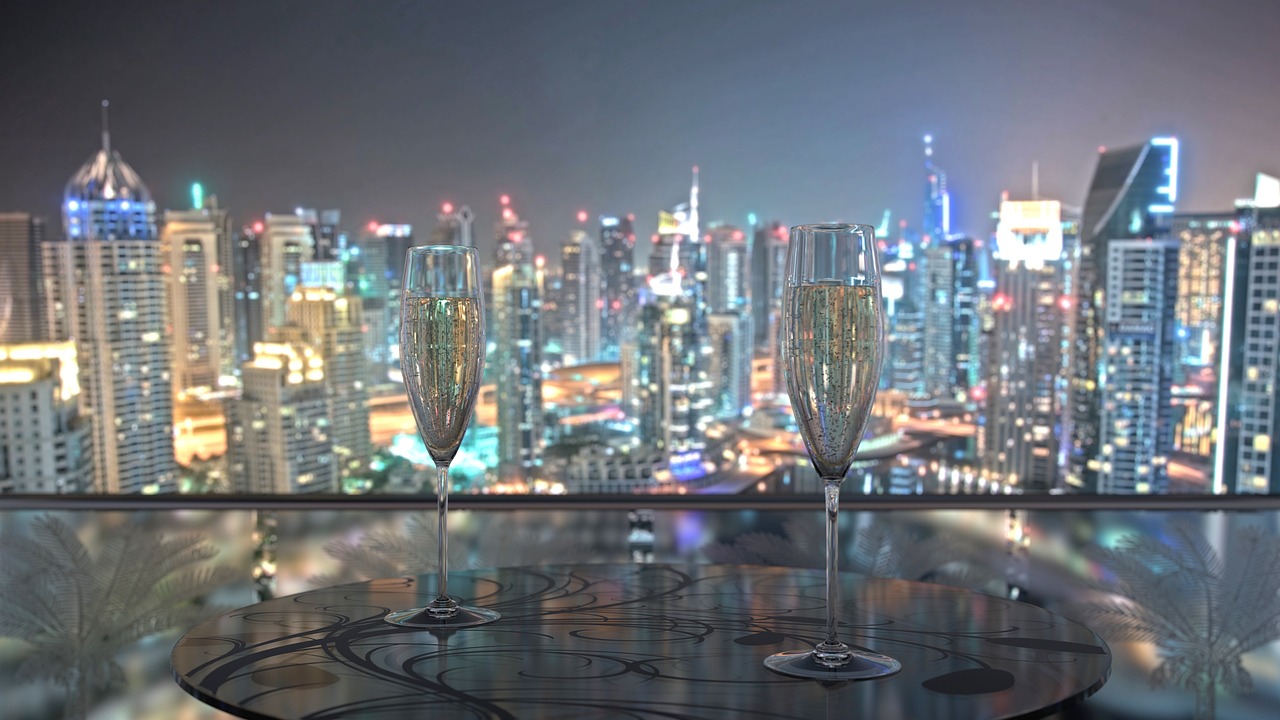 two glasses of champagne sitting on top of a table, a digital rendering, happening, cityscape background, dubai, edited, glittering