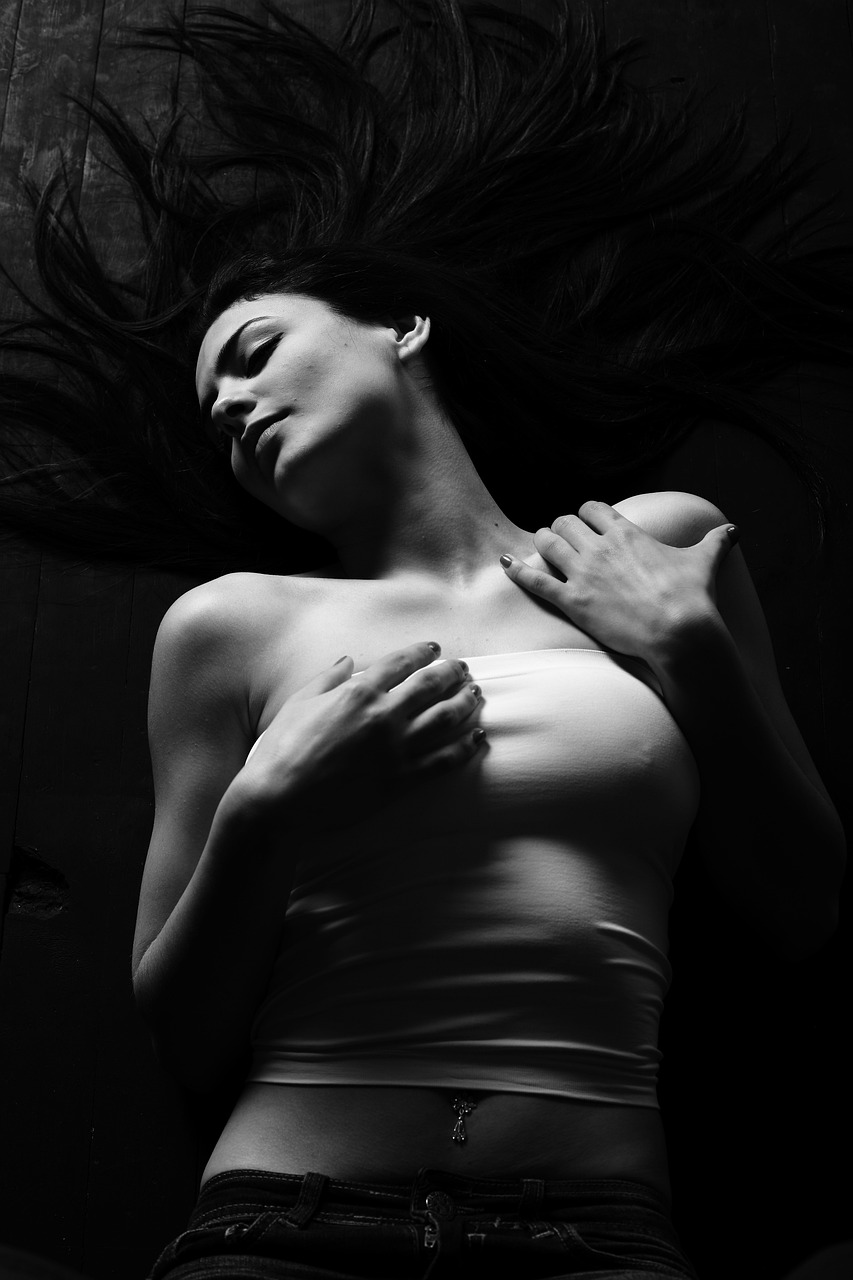 a black and white photo of a woman laying down, a black and white photo, inspired by George Hurrell, featured on cgsociety, hair floating covering chest, high contrast of light and dark, 8 k sensual lighting, young woman with long dark hair